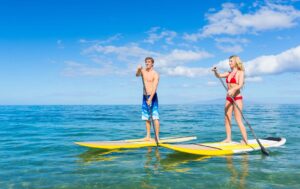 couple out paddleboarding under blue sky in Maui oceans