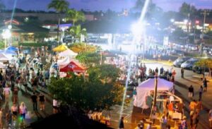 A lively Maui Friday Town Parties scene with crowds of people exploring various tents and stalls illuminated by warm lights.