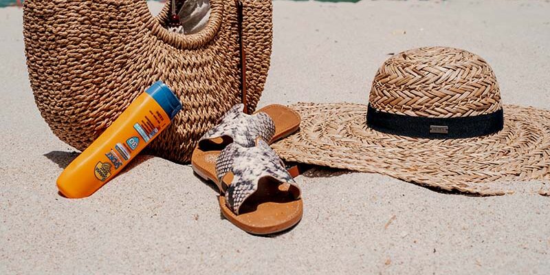 What to Pack for a Maui Kayak Tour: The Ultimate Packing List including beach bag, sunscreen, sandals, and sun hat on sandy beach